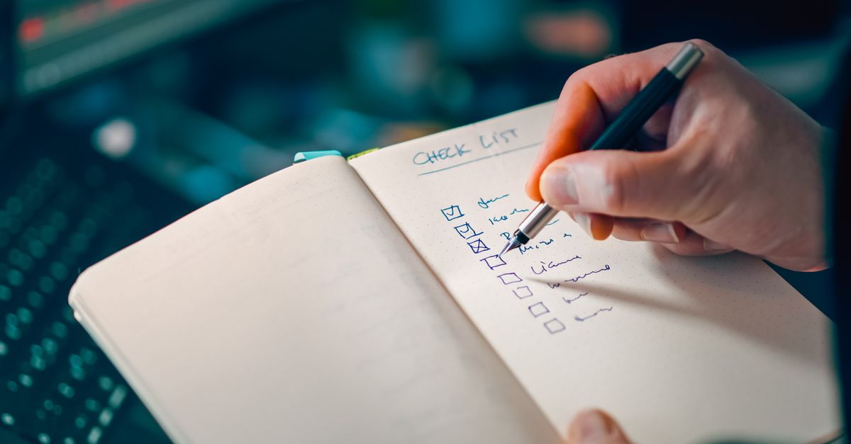 Close-up of a hand writing in a notebook with a checklist for effective task management.